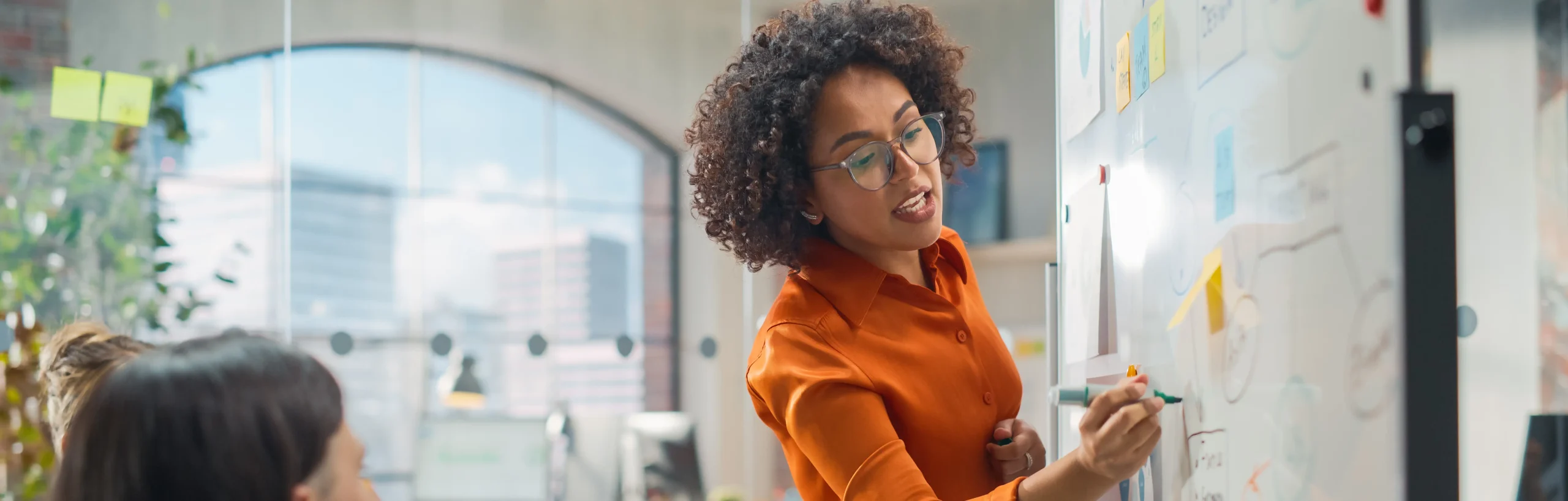 B2B lead generation - professional woman presenting business strategies on whiteboard to team in modern office