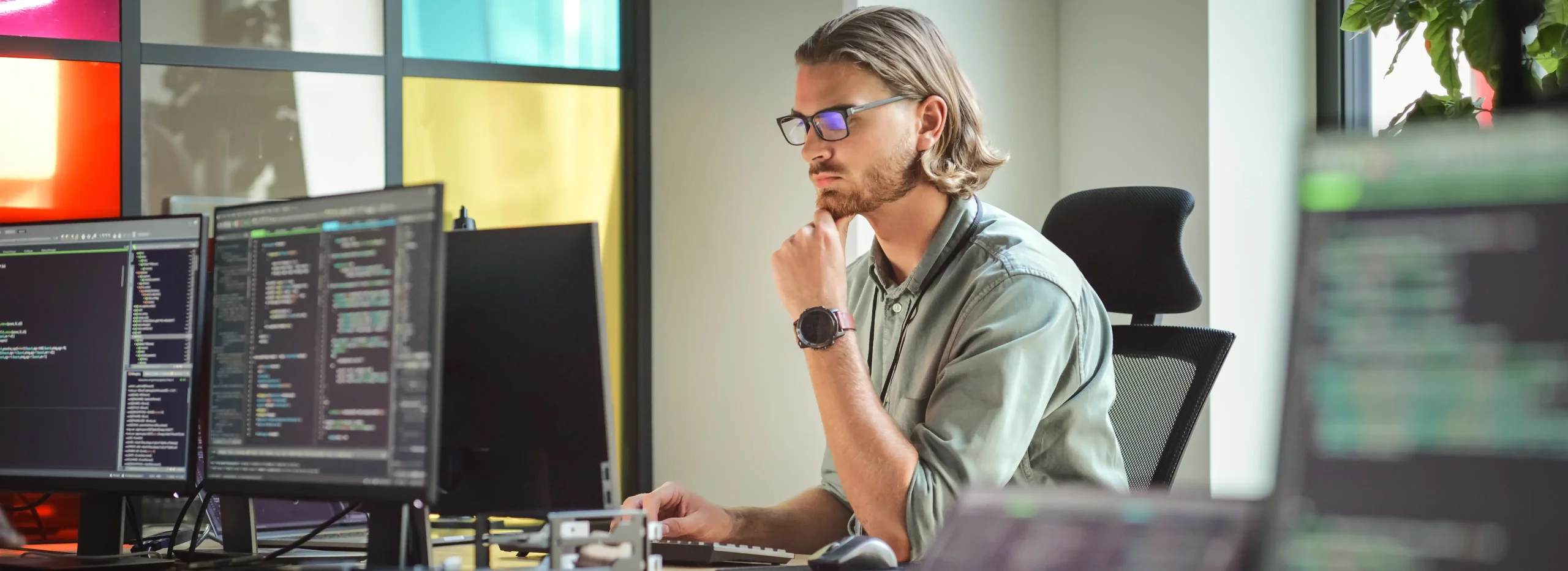 Developer writing code to scrape websites using multiple monitors with programming tools and scripts